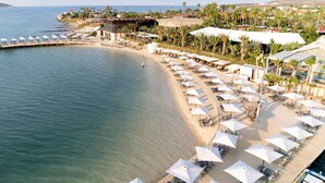 A beach resort with sun umbrellas, lounge chairs, and a view of the sea. - Biblos Beach Resort Alaçatı (Cesme)