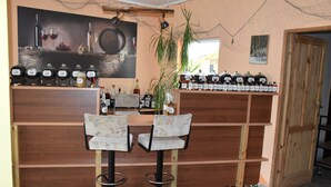 A bar area with two stools, shelves of liquor bottles, and a painting of wine bottles on the wall. - Agroturystyka u przyjaciol Soni (Zlocieniec)