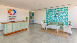 A reception area with a patterned desk, a green sofa, and a white armchair. - Fairway Sunset (Galle)