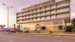 A modern multi-story building with a glass facade, multiple balconies, and a visible entrance with steps. - Fairway Sunset (Galle)