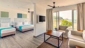 A hotel room with two beds, a TV, a balcony with a view of the beach, and a seating area with a table. - Fairway Sunset (Galle)