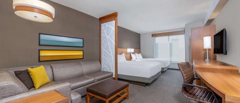 A hotel room with a sofa, a bed, a desk, and a television.