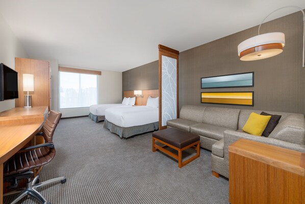 Una habitación de hotel con una cama, un sofá, un escritorio y una televisión.