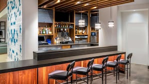 A modern bar area with a wooden counter, bar stools, and a variety of liquor bottles.
