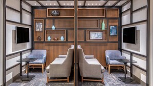 A room with a mirrored wall, wooden paneling, and two sofas facing a television.