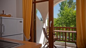 A balcony with a wooden table and chairs, a white refrigerator, and yellow curtains. - Sofia's House (Sithonia)