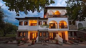 A two-story building with a patio area featuring outdoor seating and potted plants. - Sofia's House (Sithonia)