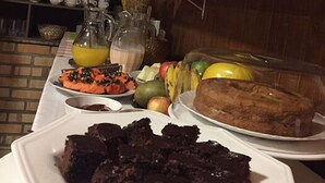 Un bufé de desayuno con diversos platos, entre ellos frutas, pastelería y un pastel de chocolate.