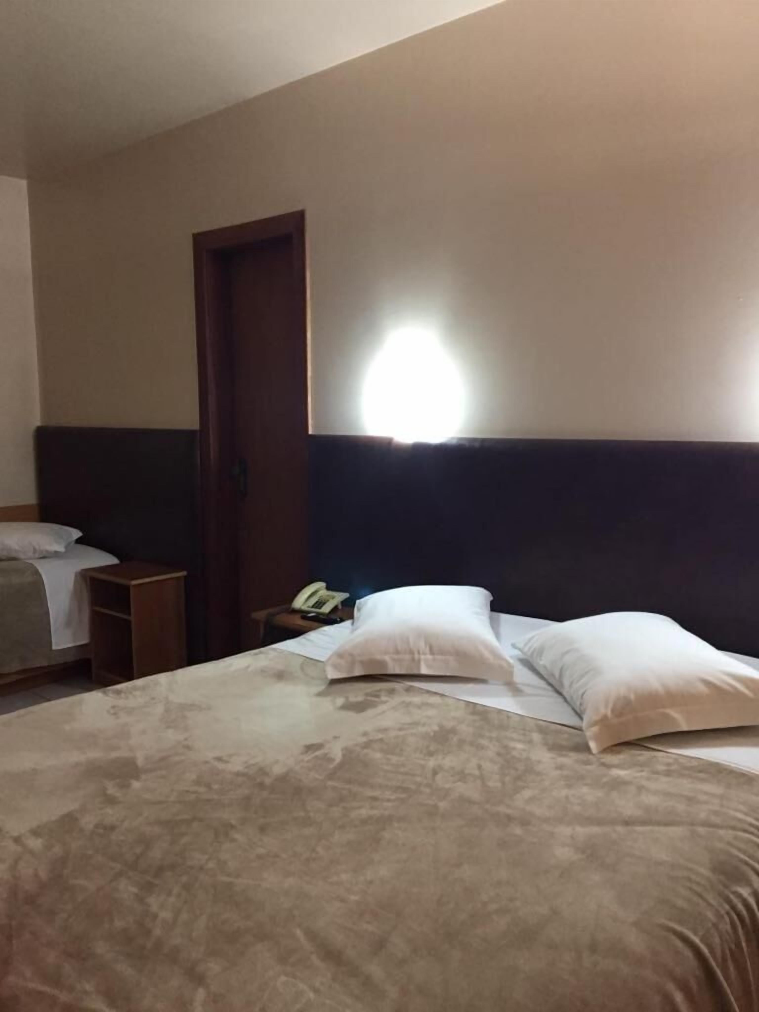 Una habitación de hotel con una cama, una mesita de noche, un teléfono y una puerta.