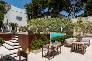 A poolside area with outdoor seating, a staircase, and a view of a building with a white facade and a garden wall.