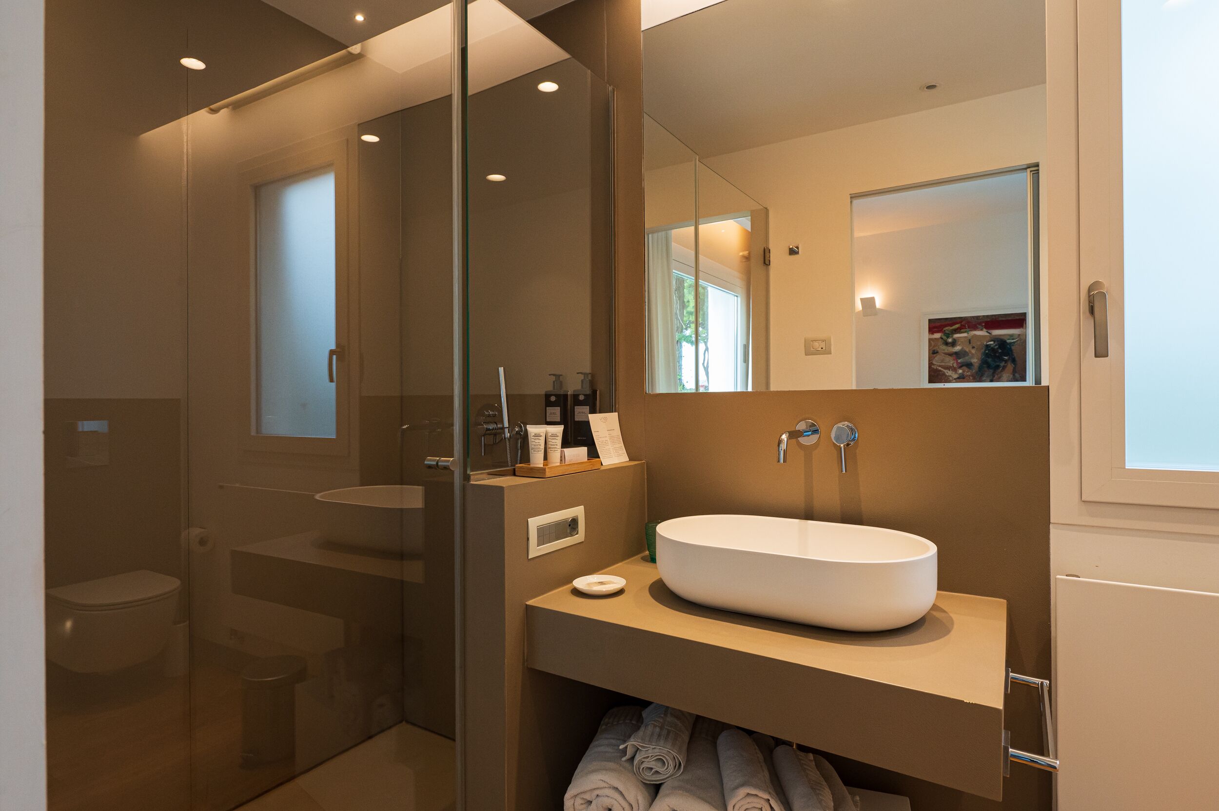 A modern bathroom with a glass-enclosed shower, a white sink, and a large mirror.