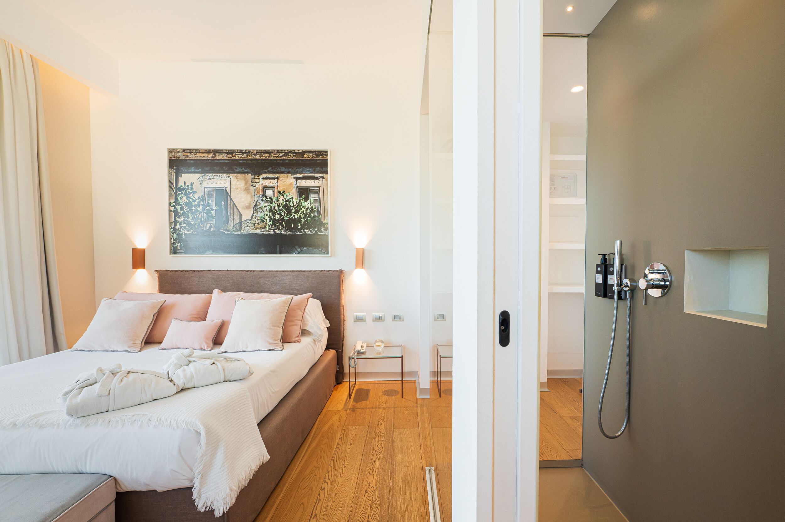 A modern hotel room with a bed, bedside lamps, a small table, and a shower area.