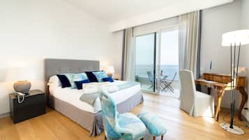 Una habitación de hotel moderna con una cama grande, un escritorio, una silla y vista al mar.