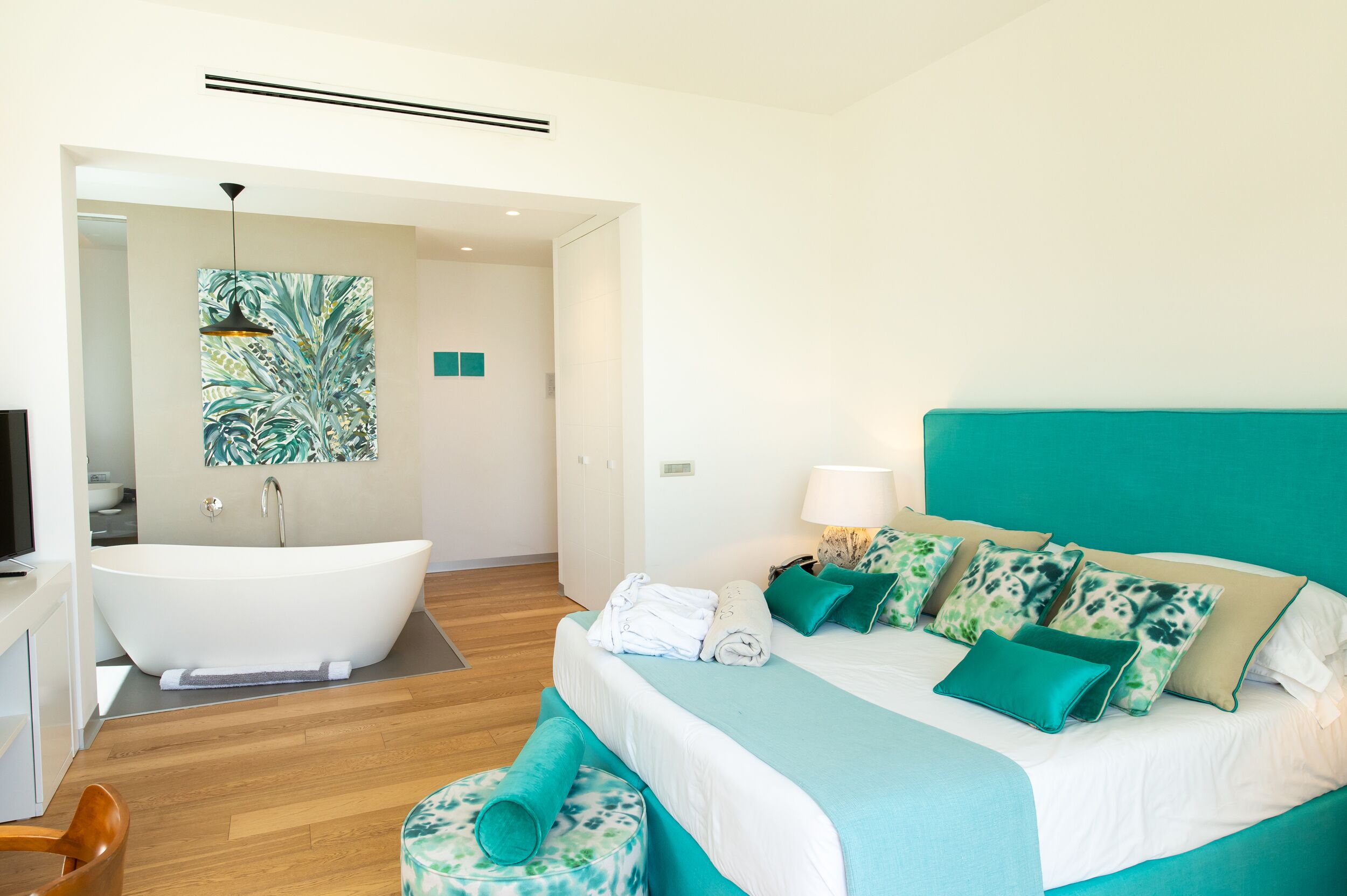A modern bedroom with a large bed, a bathtub, and a bathroom.
