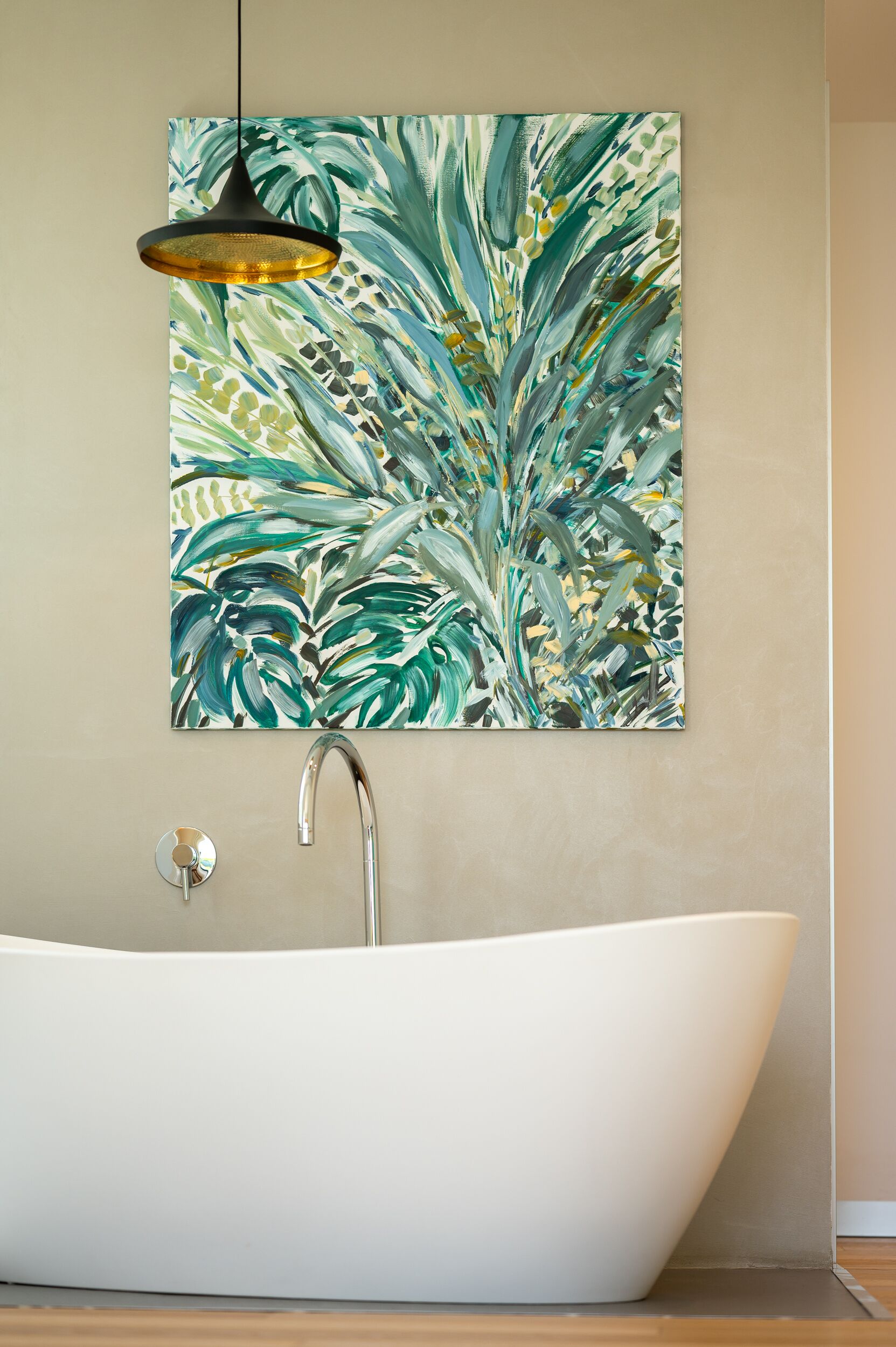 Ein modernes Badezimmer mit einer freistehenden Badewanne, einem Wandbild und einer Pendelleuchte.