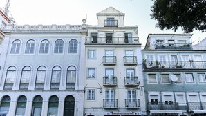 Una serie di edifici a più piani con balconi, una strada di fronte e auto parcheggiate.