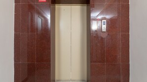Ein Aufzug mit einem Rauchverbotsschild, einem Bedienfeld und einer gefliesten Wand.