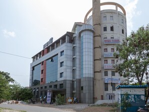 Um hotel de vários andares com design moderno, apresentando uma imponente torre cilíndrica e uma combinação de fachadas de vidro e concreto.