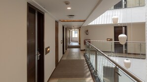 Ein Hotelkorridor mit Glastrennwand, einem Feuerlöscher und einem Deckenrauchmelder.