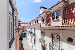 Eine enge Straße mit Gebäuden im traditionellen Stil, darunter Terrakottadächer und Balkone mit schmiedeeisernen Geländern.