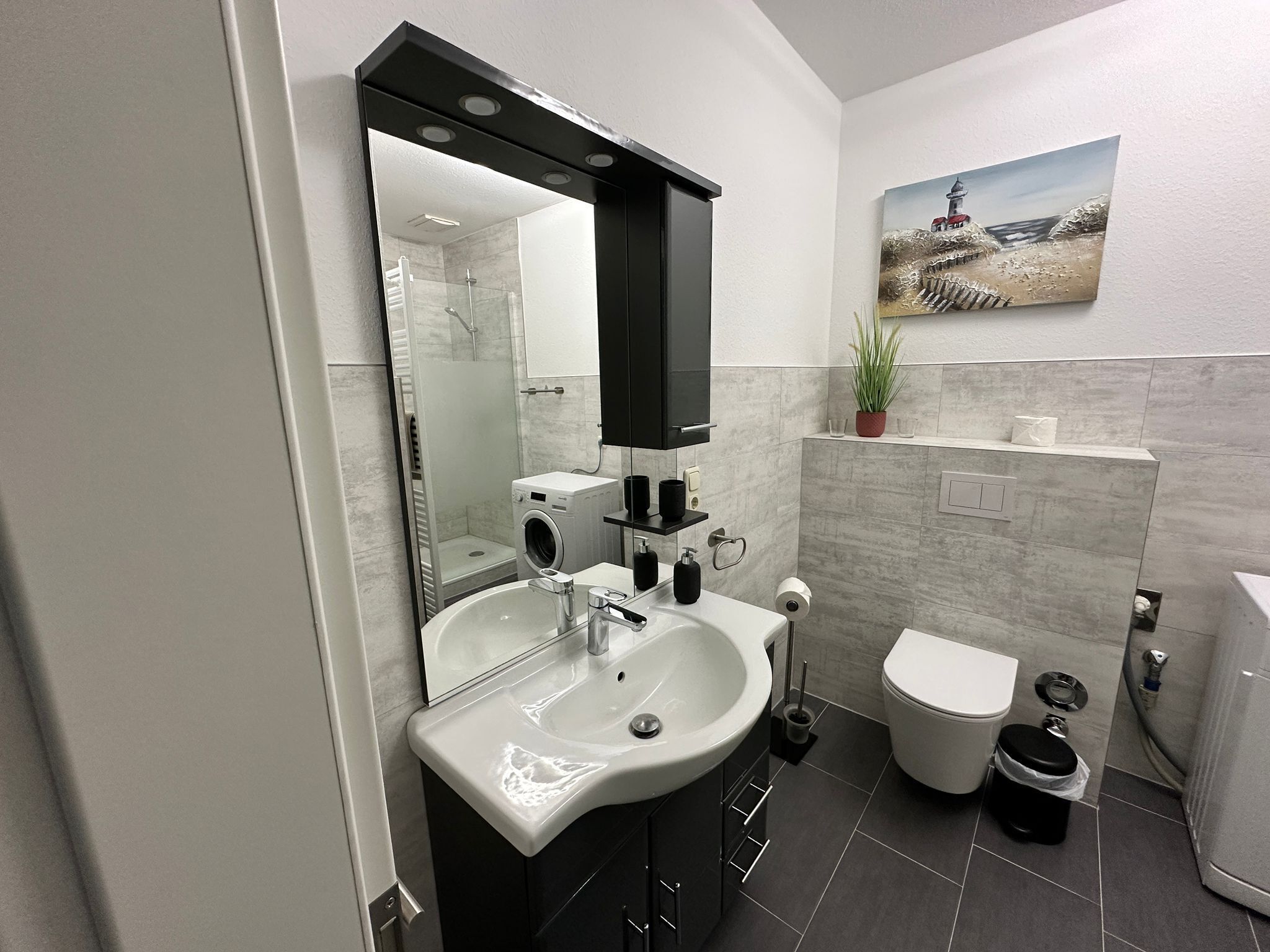 Une salle de bain moderne dotée d’un double vasque, de toilettes et d’un espace douche.