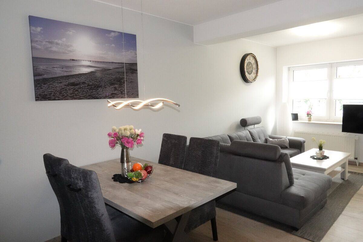 Ett modernt vardagsrum med ett matbord, en grå soffa och en tv som står på ett tv-bord.