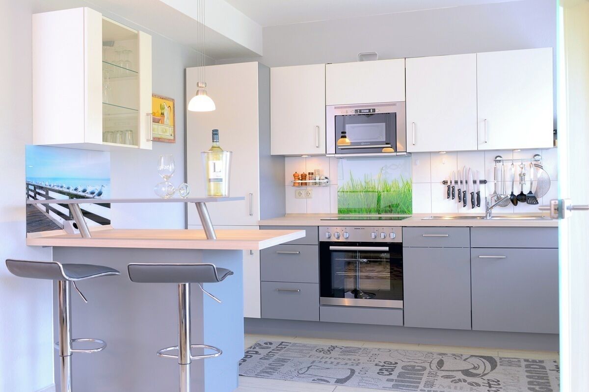 A modern kitchen with a built-in oven, a microwave, and a bar area with stools.