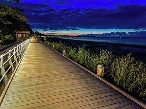 Ein hölzerner Steg führt zu einem Pier mit Blick auf das Wasser und ferne Berge.