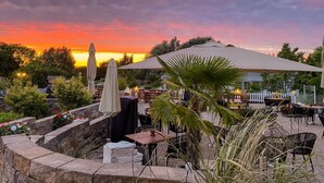 An outdoor seating area with stone planters, umbrellas, and tables. - Hotelanlage Tarnewitzer Hof (Boltenhagen)