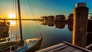 A calm marina with docked boats and wooden buildings reflecting the sunset. - Hotelanlage Tarnewitzer Hof (Boltenhagen)