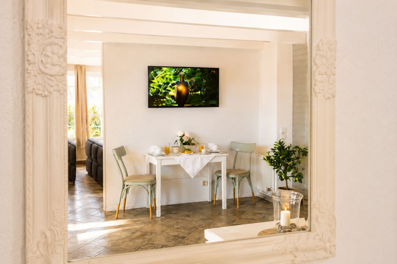 A dining area with a table, chairs, a TV, and a plant.