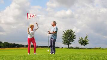 A golf course with a flag marked '15' and two people standing on the green.