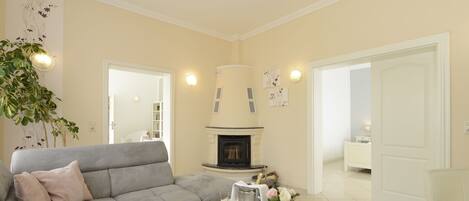A living room with a grey sofa, a white coffee table, a fireplace, and a large plant.