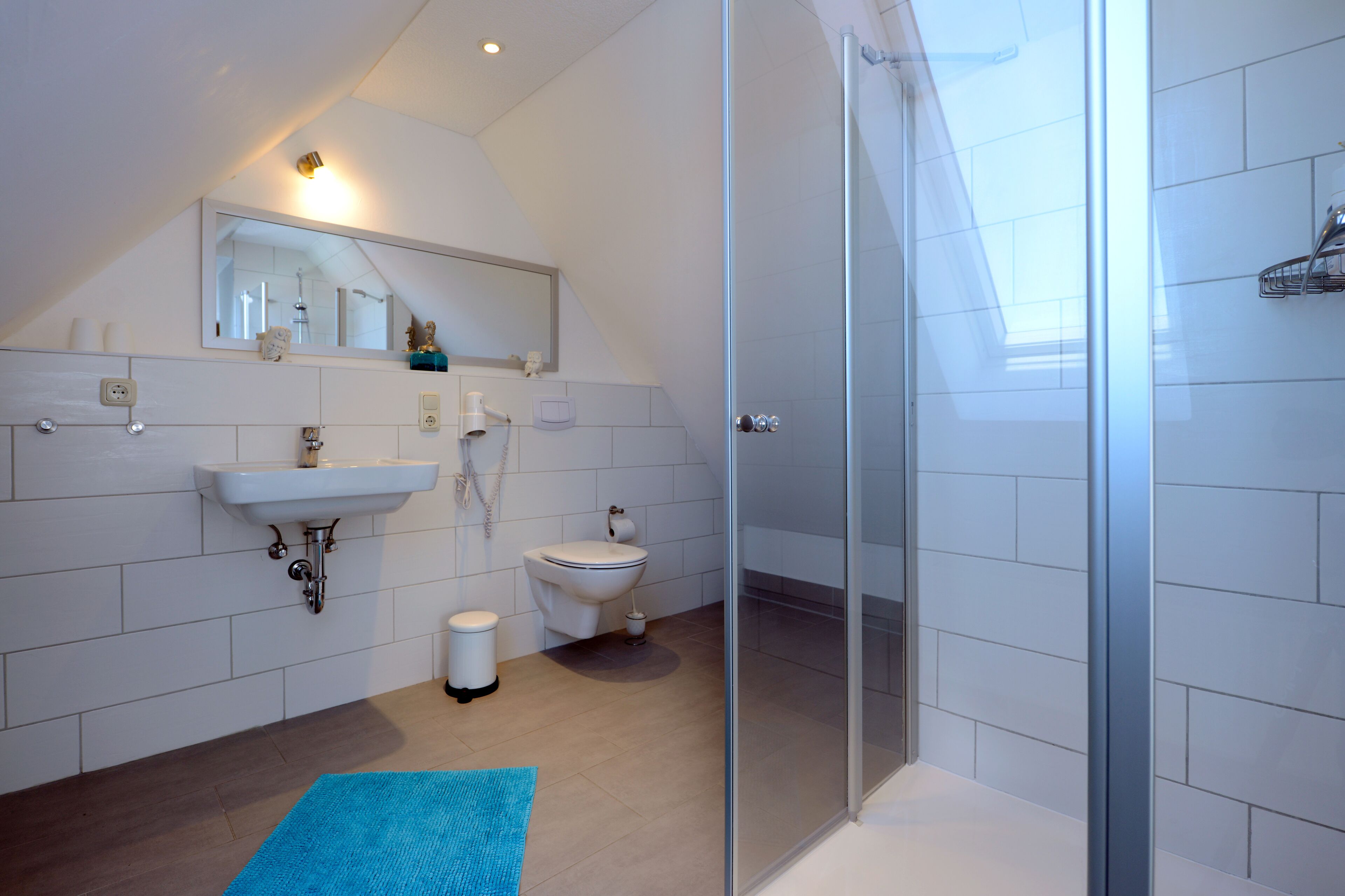Un bagno moderno con cabina doccia in vetro, lavandino e water.