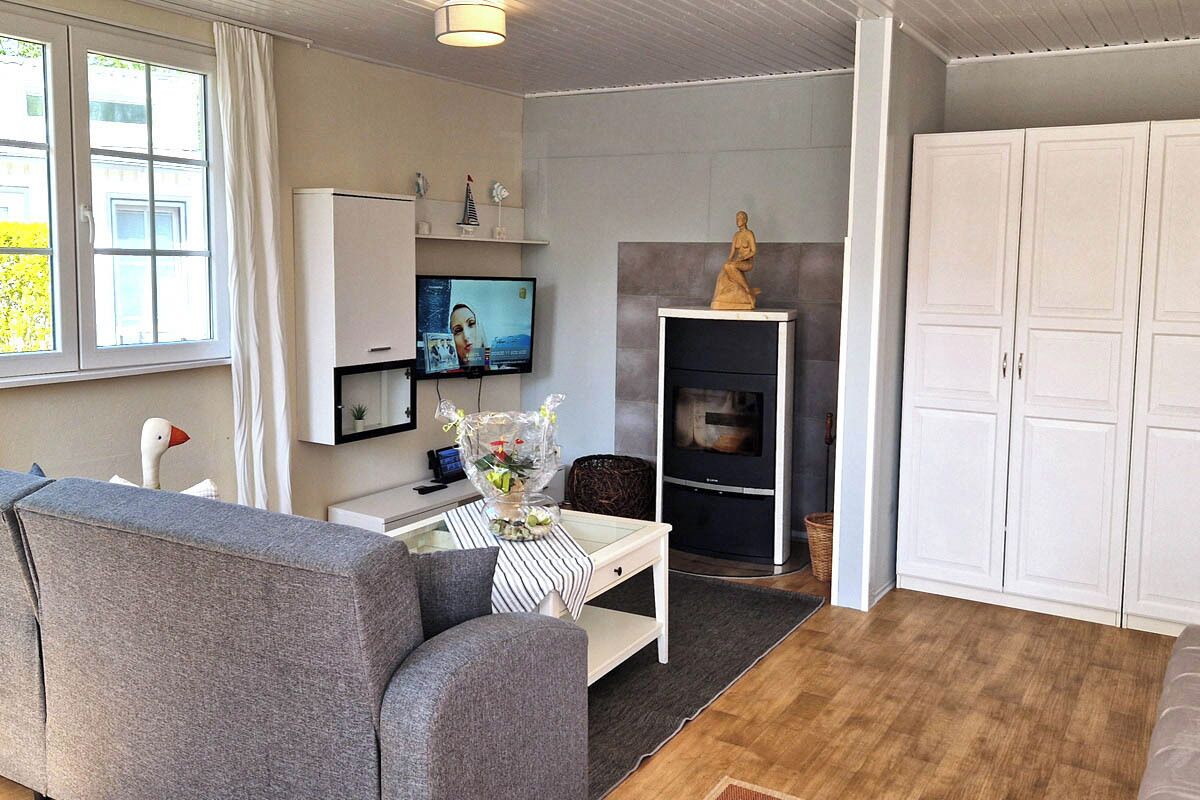 A modern living room with a grey sofa, a flat-screen TV, a fireplace, and white cabinets.
