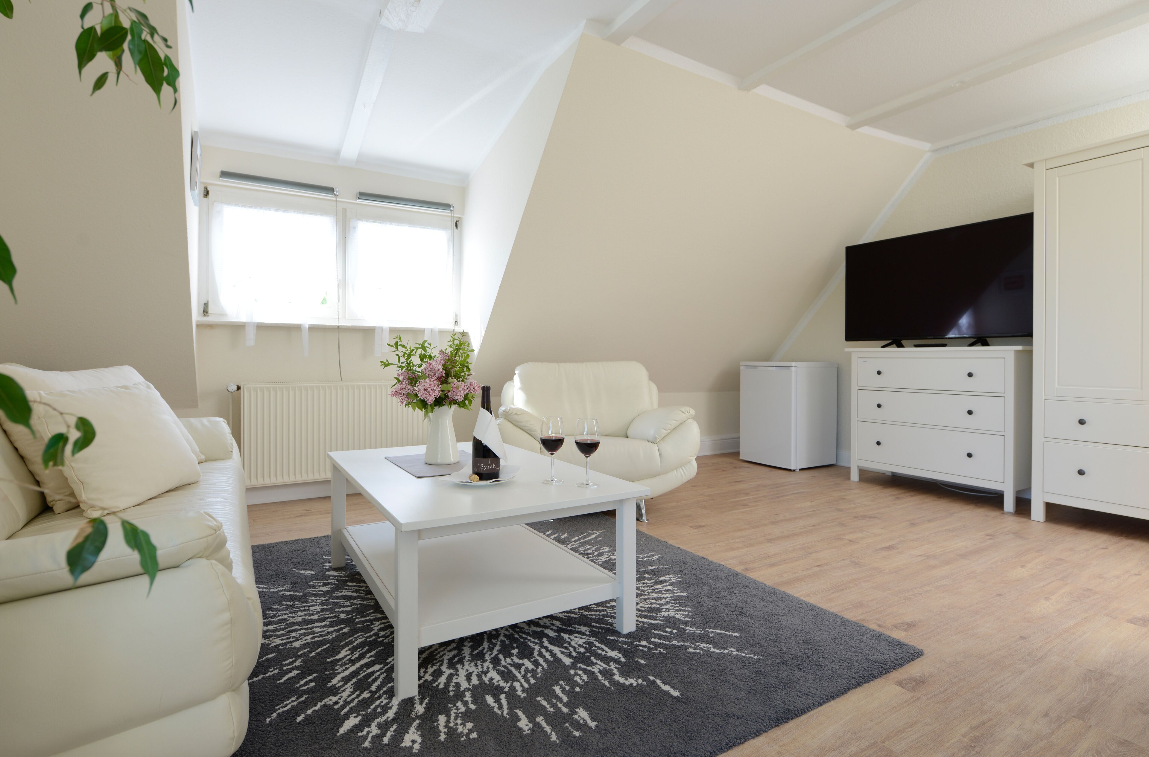 A modern living room with a white sofa, a coffee table, and a TV on a stand.