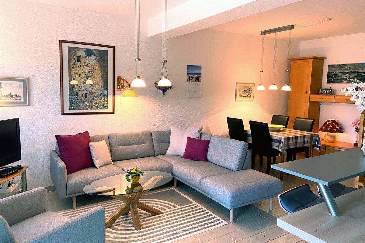 Un salon moderne comprenant un canapé, une table basse et un coin repas. On y trouve également un téléviseur, des œuvres d’art et un meuble.