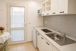 A compact kitchen with a built-in microwave, a sink, and a small refrigerator.