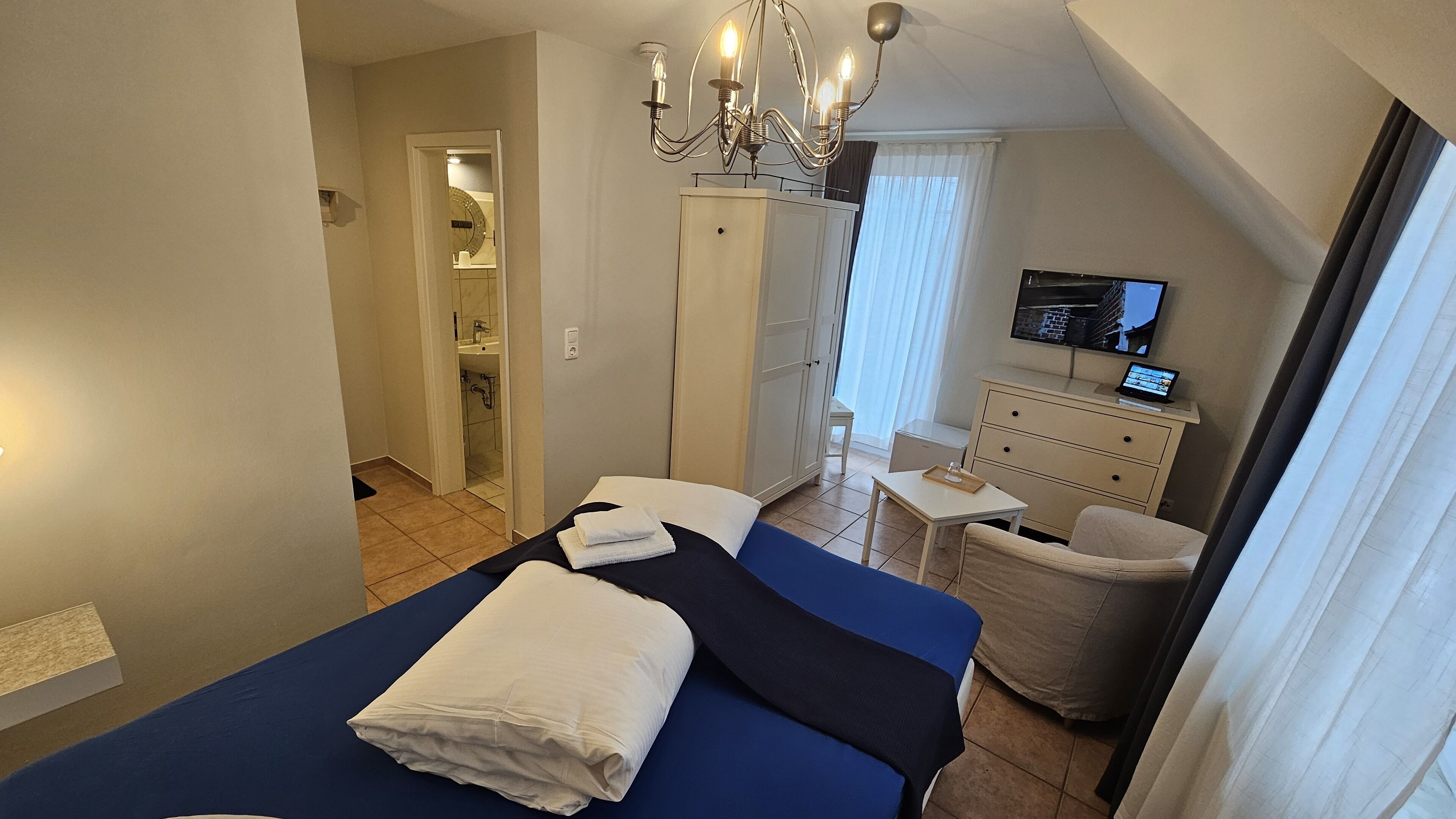 Un dormitorio con cama, escritorio, televisor y armario.