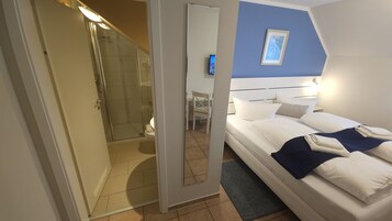 Una habitación de hotel con cama, escritorio, silla y zona de ducha.