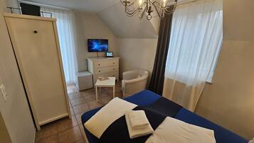 Une chambre à coucher comprenant un lit, un bureau, une chaise, une télévision et une armoire.