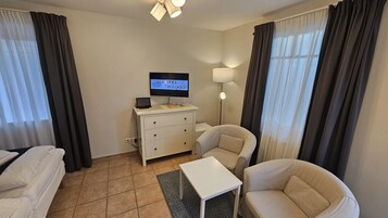 Una habitación de hotel con una cama, dos sillones, una mesita, un televisor en una cómoda y una lámpara.