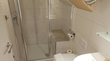 Une salle de bain avec une douche à parois de verre, des toilettes et un lavabo.