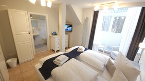 A hotel room with a bed, a TV, a desk, and a bathroom. - Hotel Garni Auszeit (Boltenhagen)