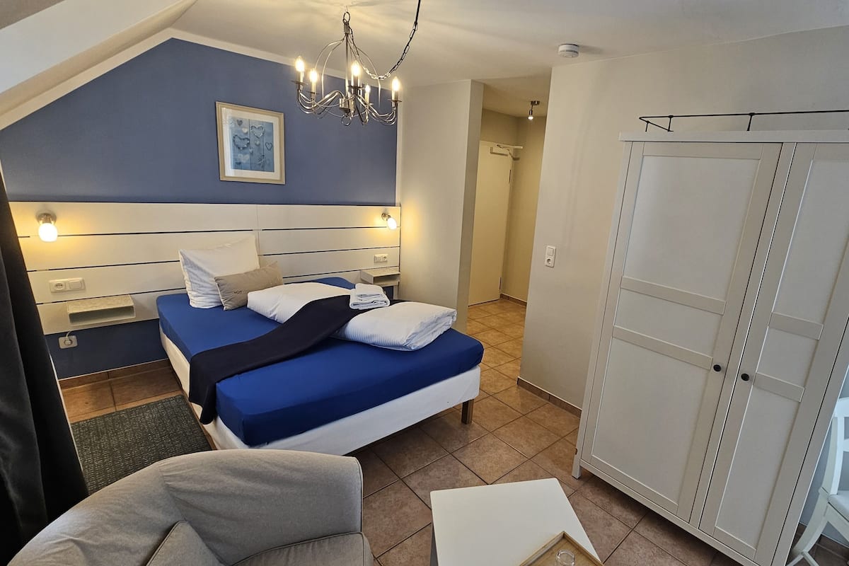 A bedroom with a bed, bedside tables, a wardrobe, a chair, and a small table.
