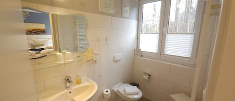 Un baño con lavamanos, inodoro y ventana.