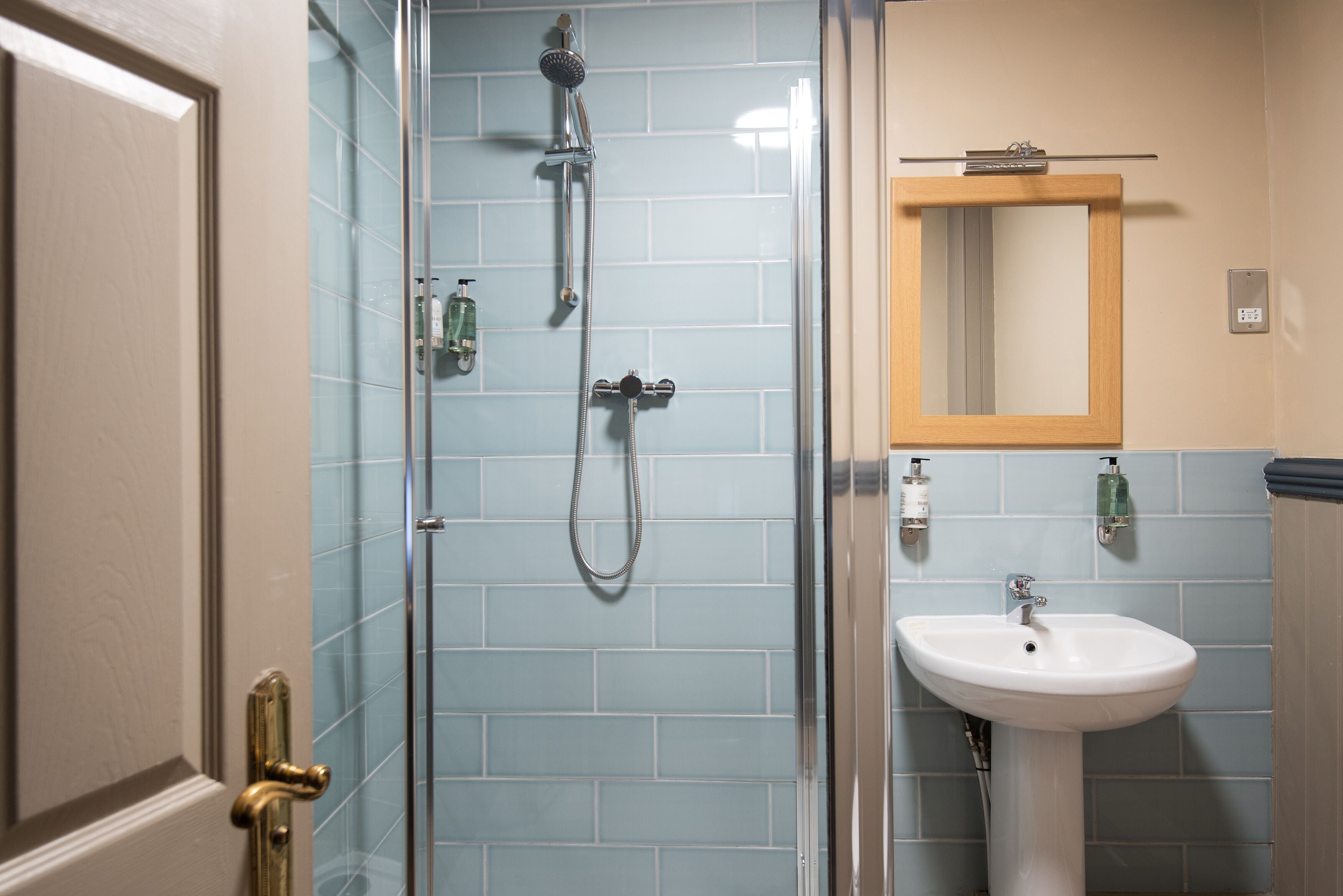 Une salle de bain avec une douche à parois de verre, un lavabo blanc et un miroir au-dessus.