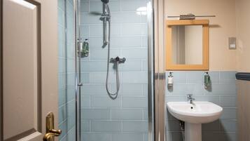 Une salle de bain avec une douche à parois de verre, un lavabo blanc et un miroir au-dessus.