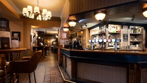 A bar area with a counter, stools, and a variety of bottles and glasses. - The Kingslodge Inn - The Inn Collection Group (Durham)