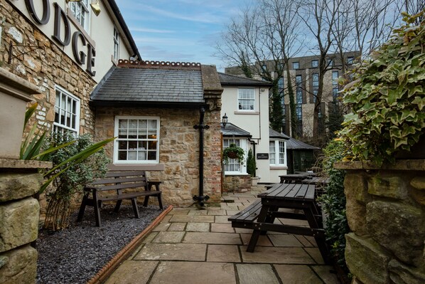 A stone building with a sign reading "RODGUE" and outdoor seating area with benches and tables. - The Kingslodge Inn - The Inn Collection Group (Durham)